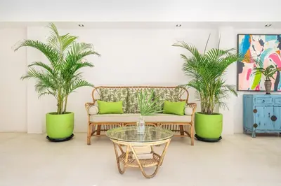 a living room with a couch and two palm trees at Ocean Two 1BR Villa Honeymoon Seminyak in Seminyak