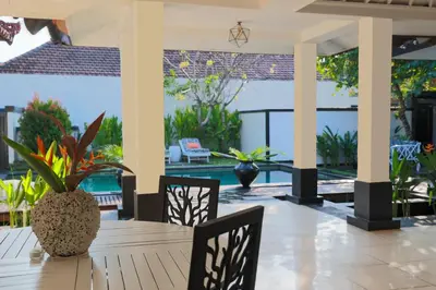 a dining room table with chairs and a view of a pool at Ocean Two 4BR Family Retreat Oberoi in Seminyak