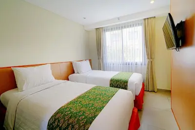 a hotel room with two beds and a television at Savvoya Hotel Seminyak in Seminyak