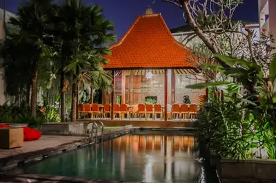 a swimming pool in front of a building with an orange roof at Savvoya Hotel Seminyak in Seminyak