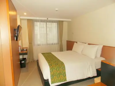 a hotel room with a white bed and a window at Savvoya Hotel Seminyak in Seminyak