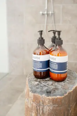 two bottles of soap sitting on top of a log at Luxurious & Bespoke Upscale 3BR Villa in Canggu in Canggu