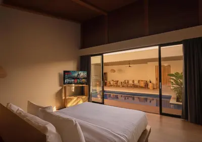 a bedroom with a large bed and a swimming pool at Kinama Villa Jimbaran Bali in Jimbaran
