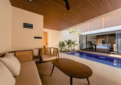a living room with a couch and a swimming pool at Kinama Villa Jimbaran Bali in Jimbaran