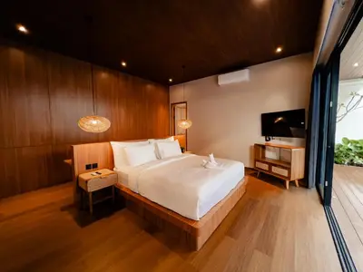 a bedroom with a large bed and a television at Kinama Villa Jimbaran Bali in Jimbaran