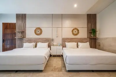 two beds in a room with white sheets at Puri Ratu Jimbaran Villa by Betterplace in Jimbaran