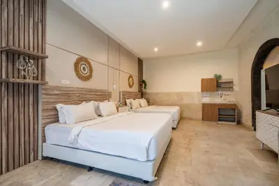 two beds in a hotel room with a television at Puri Ratu Jimbaran Villa by Betterplace in Jimbaran