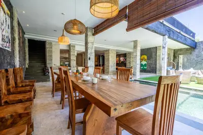 a dining room with a wooden table and chairs at Puri Ratu Jimbaran Villa by Betterplace in Jimbaran