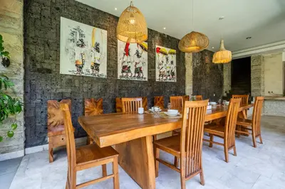 a dining room with a wooden table and chairs at Puri Ratu Jimbaran Villa by Betterplace in Jimbaran