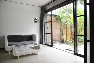 a living room with a couch and a glass door at Casa Veluna - Seminyak in Seminyak