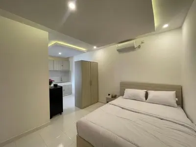 a bedroom with a large bed and a kitchen at Mopoe Guesthouse in Sanur