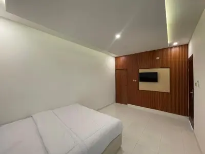 a bedroom with a bed and a tv on a wall at Mopoe Guesthouse in Sanur