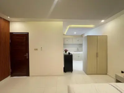 a room with a bed and a door and a kitchen at Mopoe Guesthouse in Sanur