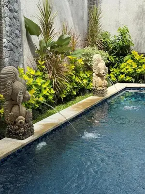a garden with two statues next to a swimming pool at Villa Jiwanta by Maheswara in Kerobokan