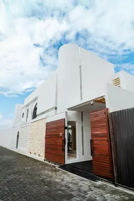 a white building with wooden doors on the side at Jivani Villa - 9 min to Nusa Dua Beach - Brand New, Cinema Room, BBQ, 3Bdr in Jimbaran