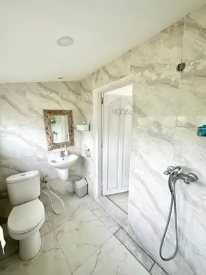 a bathroom with a shower and a toilet and a sink at Wangi Melati Homestay in Kerobokan