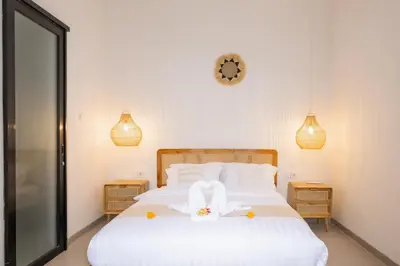 a bedroom with a white bed and a clock on the wall at La Casa Gomes in Nusa Dua
