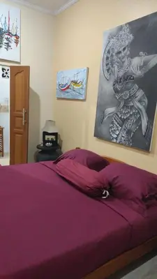 a bedroom with a purple bed with a painting on the wall at Villa Harmony Moon in Denpasar