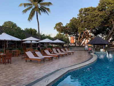 a row of chairs and umbrellas next to a swimming pool at The Jayakarta Residence 2BR Bali in Denpasar