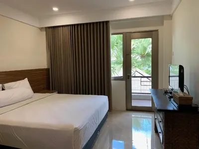 a bedroom with a bed and a desk and a television at The Jayakarta Residence 2BR Bali in Denpasar