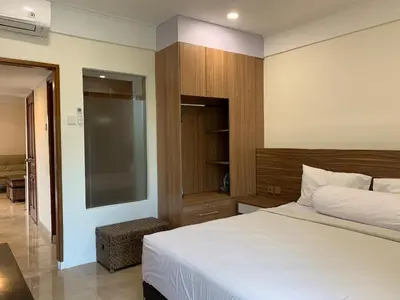 a bedroom with a large white bed and a mirror at The Jayakarta Residence 2BR Bali in Denpasar