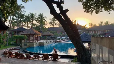 a woman sitting in chairs by a pool at a resort at The Jayakarta Residence 2BR Bali in Denpasar