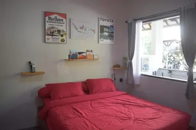 a bedroom with a red bed with a window at Banana Room Near to Kuta Legian Beach in Legian