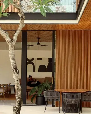 a person sitting on a couch in a room with a tree at Villa Semilir Sendja, Canggu in Canggu