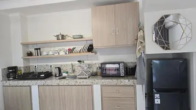 a kitchen with a sink and a microwave and a refrigerator at Villa 1 Kavi minimalis 1 Kamar di Sanur in Sanur
