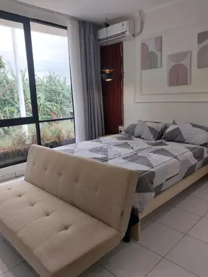 a bedroom with a bed and a couch and a window at Villa 1 Kavi minimalis 1 Kamar di Sanur in Sanur