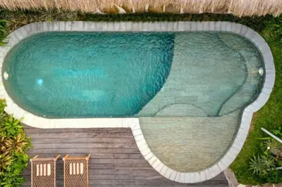 a large swimming pool with two chairs next to it at Adena Modern Paradise 3 BR Private Pool Villa in Kerobokan