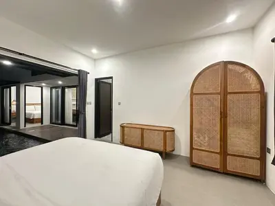 a bedroom with a white bed and a wooden door at Della Solea Seminyak in Seminyak