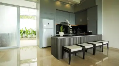 a kitchen with black cabinets and a counter with stools at Mahita Garden Villa 3 Bedroom with Amazing view in Jimbaran