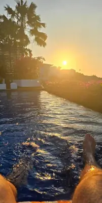 a person laying in the water as the sun sets at Mahita Garden Villa 3 Bedroom with Amazing view in Jimbaran