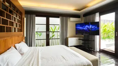 a bedroom with a bed and a flat screen tv at Mahita Garden Villa 3 Bedroom with Amazing view in Jimbaran
