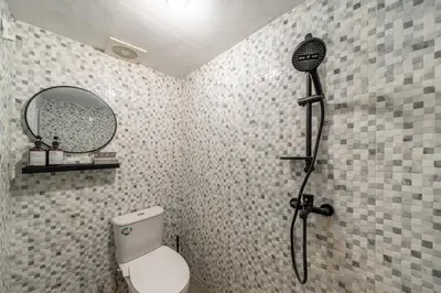 a bathroom with a shower with a toilet and a mirror at Cozy Mezzanine Near Airport & Jimbaran Beach in Ngurah Rai International Airport