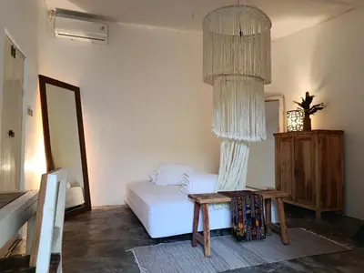 a bedroom with a bed and a table and a chandelier at Gusti Ayu Private Bali House - 2 Bedrooms near Canggu & Seminyak in Kerobokan