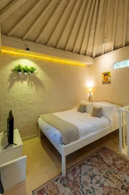 a bedroom with a bed and a tv in a room at Palm Villa 4 , Seminyak Center in Seminyak
