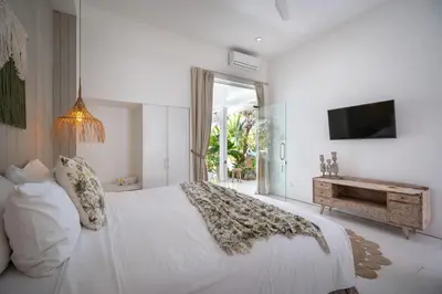 a white bedroom with a bed and a television at Villa 888 Eat Shop Play - 3BR Private Pool Oberoi in Seminyak