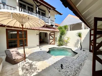 a patio with an umbrella and a swimming pool at Charming Two Bedroom Villa Near Seminyak Beach in Seminyak