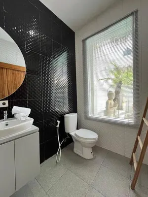 a bathroom with a toilet and a sink and a window at Ametys 1 Villa - Cozy 2BR Villa with Private Pool & Prime Seminyak in Seminyak