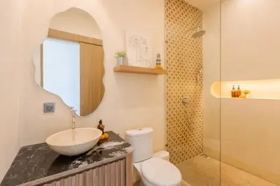 a bathroom with a sink and a toilet and a mirror at The Shalak Villa Bali in Denpasar