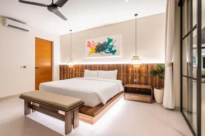 a bedroom with a large white bed and a table at Villa Rice Kerobokan in Kerobokan
