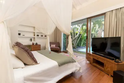 a bedroom with a bed with a television and a window at Villa Anicca - Family-Friendly 4BR Villa Umalas With Private Pool And Rooftop Lounge in Canggu
