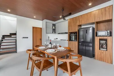 a kitchen with a wooden table and chairs and a refrigerator at New Villa 3BR Umalas Pool Near Seminyak and Canggu in Canggu