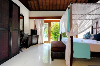 a bedroom with a bed with a canopy and a television at Superb and Elegant 3-Bedroom Villa Close to the Beach in Seminyak