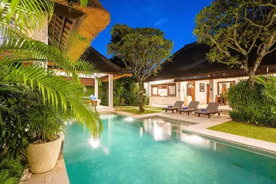 a swimming pool in front of a house with palm trees at Superb and Elegant 3-Bedroom Villa Close to the Beach in Seminyak