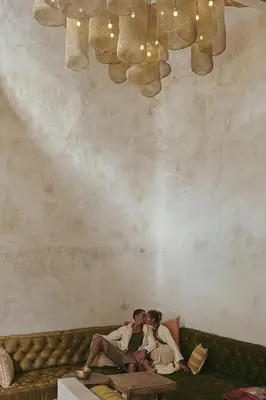two people sitting on a couch under a chandelier at The Turiya - Redefining luxury in Canggu in Canggu