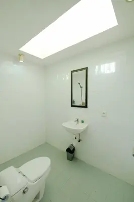 a white bathroom with a toilet and a sink at Villa Beji Ayu Seminyak - 2 Bedroom Private Pool in Seminyak