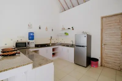 a kitchen with white cabinets and a refrigerator at Villa Beji Ayu Seminyak - 2 Bedroom Private Pool in Seminyak
